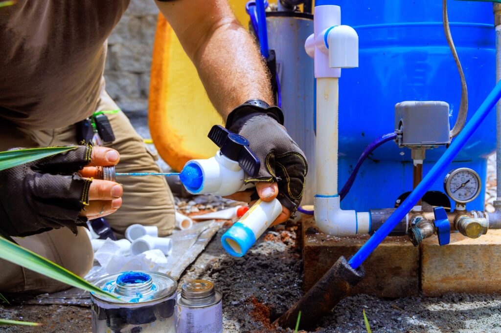 Gluing pvc pipe, plumber applies glue connected to a water supply artesian well system pump house